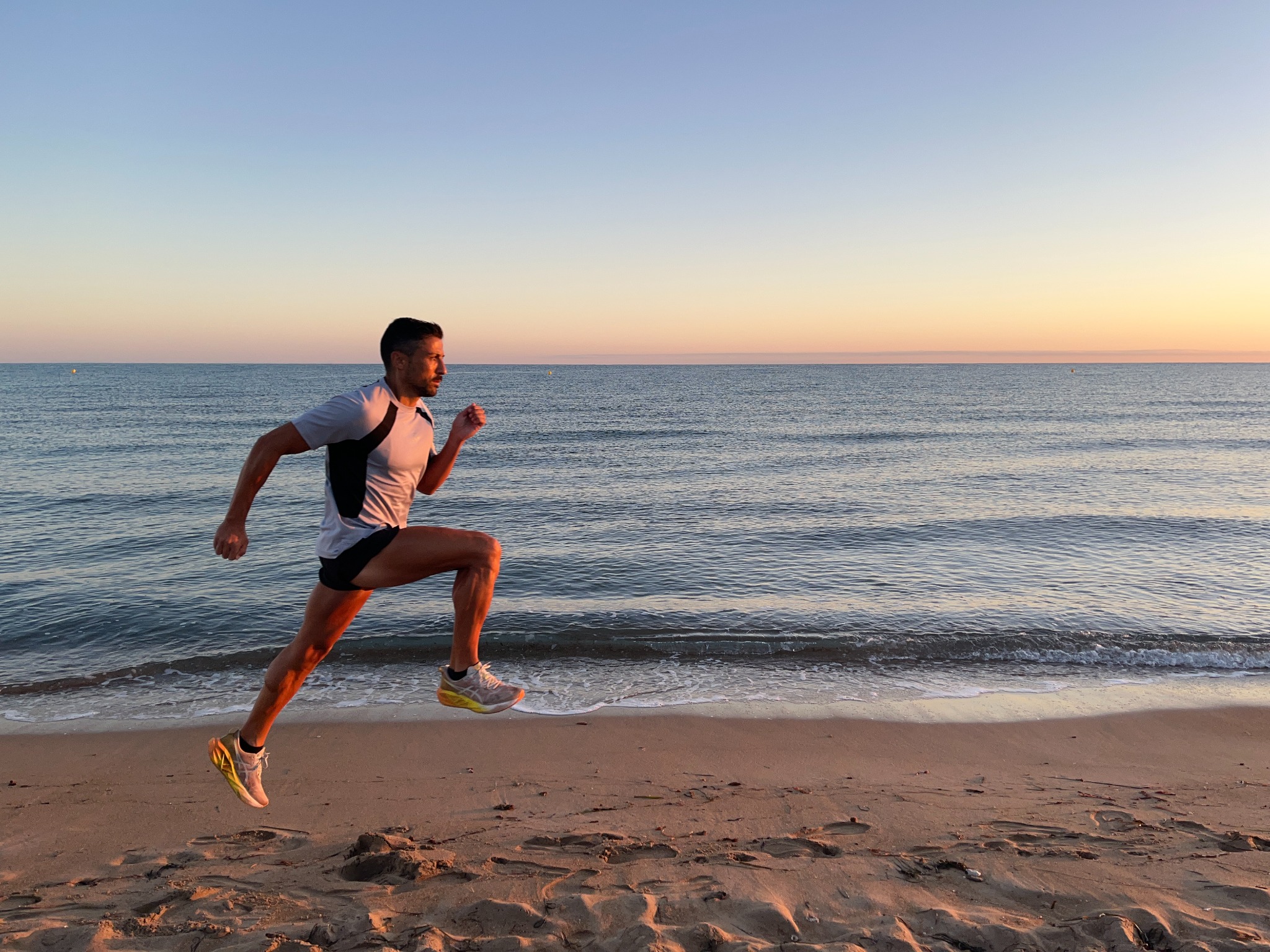 Álex corriendo junto al mar al atardecer